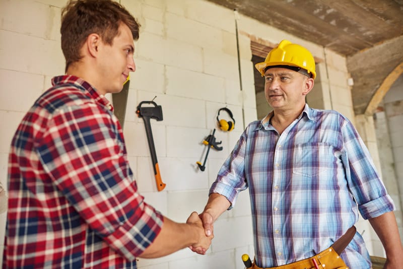 Poignée de main entre un entrepreneur et un particulier sur un chantier
